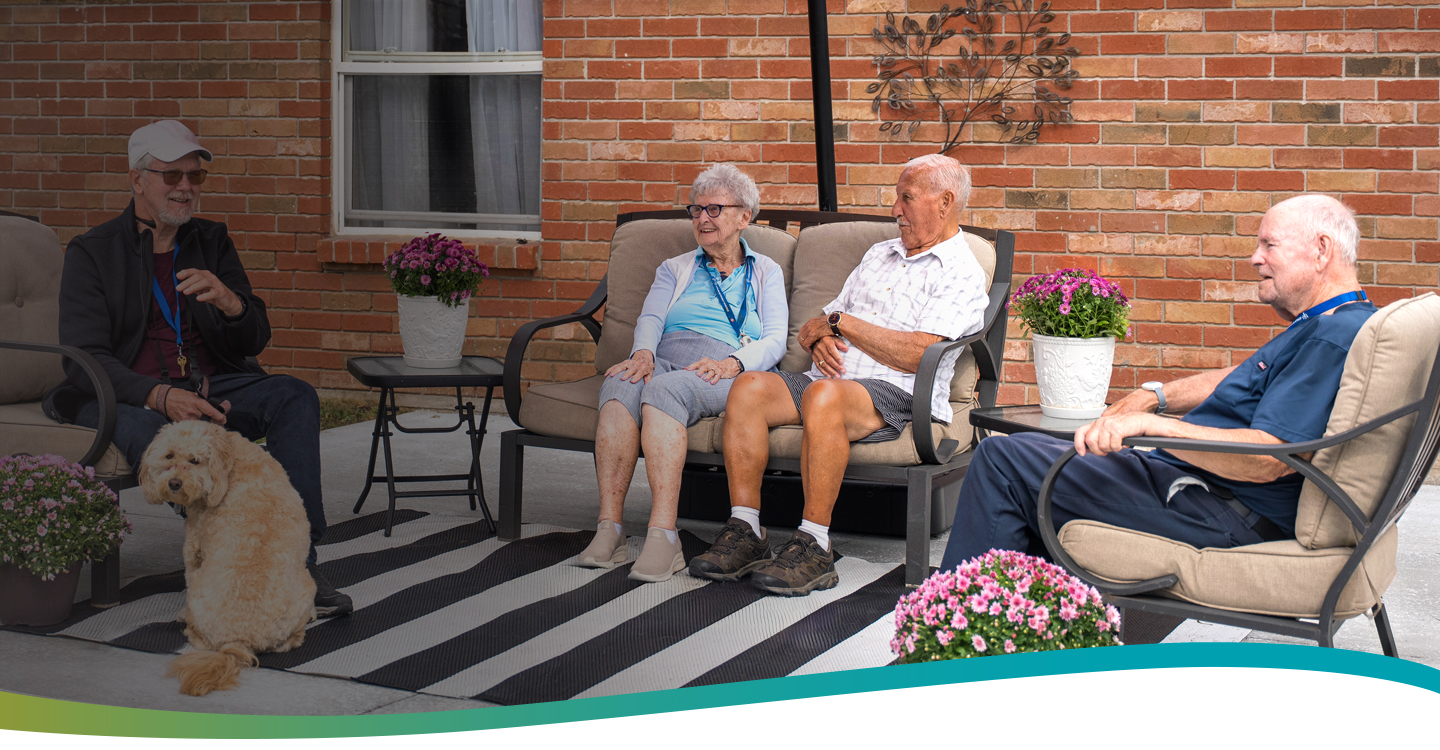 Residents relaxing on the patio with their dog, enjoying a sunny afternoon at Atrium Retirement Residence in Orillia.