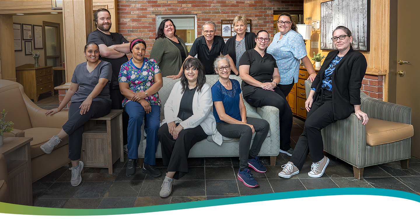 Group of Atrium Retirement Residence team members seated together on a couch in the bright atrium