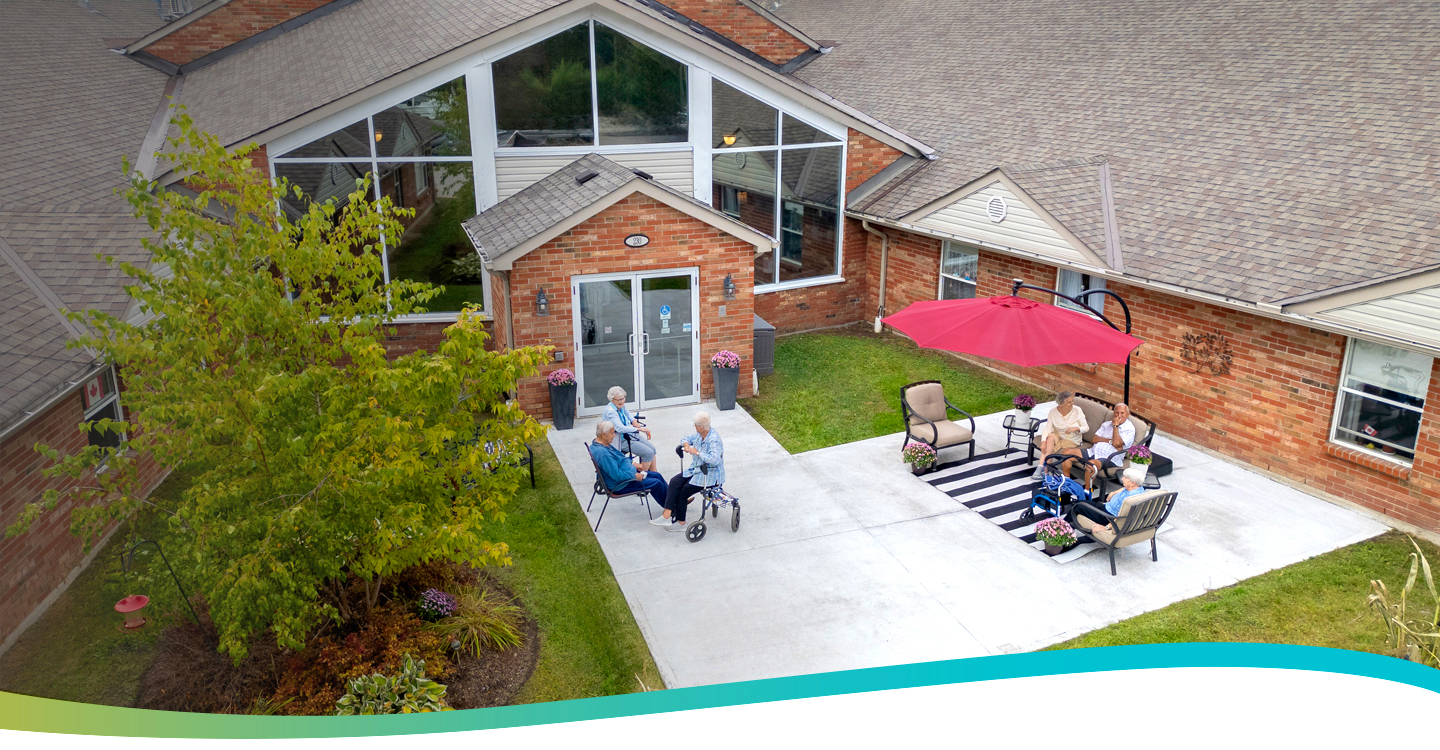 Residents enjoying the outdoor patio in front of the building, seen from above at Atrium Retirement Residence in Orillia.